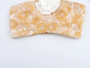 Detail eines goldenen Jacquard-Crop-Tops mit eleganter weißer 3D-Blütenapplikation
