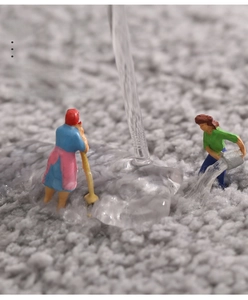Makroaufnahme der dicken Badematte zeigt schnelle Wasseraufnahme mit Miniatur-Reinigungsfiguren