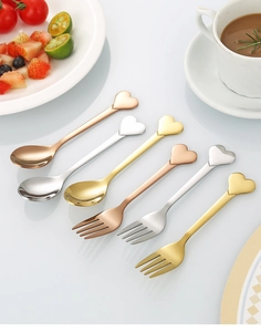 Close-up of heart-shaped stainless steel spoons and forks set in gold and silver finish