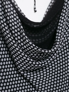 Close-up of cowl neck detail on a black polka dot vacation style slip dress fabric