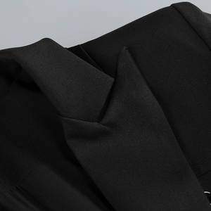 Detail of a black blazer dress featuring peak lapel and fine twill fabric texture