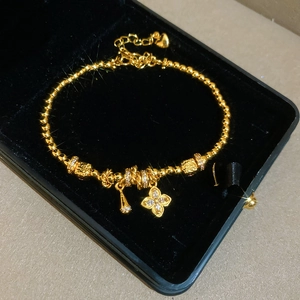 Macro shot of 24K gold plated beaded flower bracelet with zircon clover in velvet box