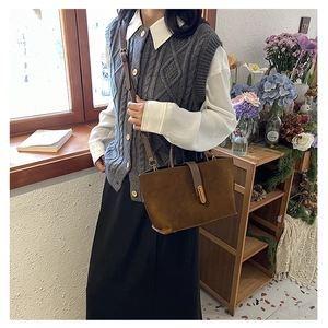 Detail of dark brown suede tote bag with gold metal clasp and adjustable leather strap