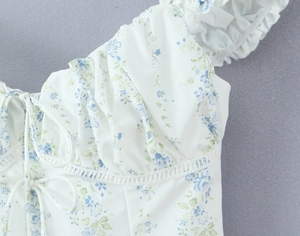 Close-up of floral top featuring lace edges, ruched neckline and tie-up details