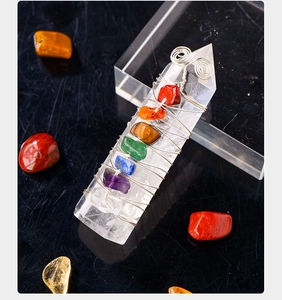 Detailed macro shot of 7 Chakra crystal pendant wrapped in silver wire on black surface
