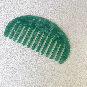 Detailed close-up of a green marble pattern wide-tooth comb made of acetate material