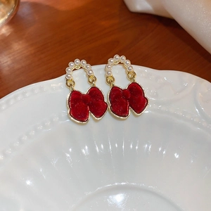 Détail de boucles d'oreilles nœuds rouges floqués avec anneaux dorés et perles