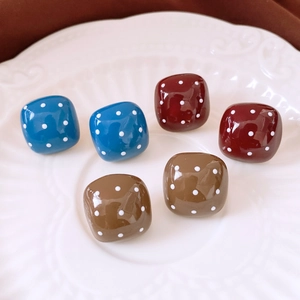Macro shot of retro resin square stud earrings with white polka dots in a white tray
