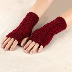 Close-up of wine red cable knit fingerless gloves showing textured stitch and ribbed cuffs