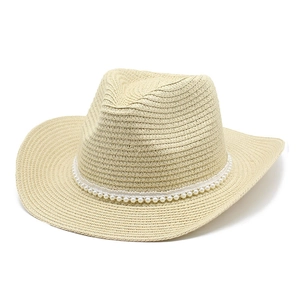 Détail d'un chapeau de cowboy en paille beige avec une bande de perles blanches élégantes