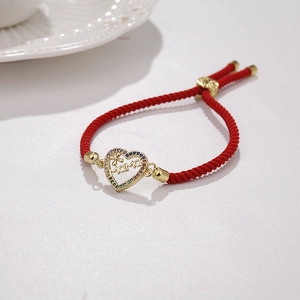Macro shot of 18K gold heart charm with MAMA cutout and colorful zircons on red rope