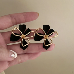 Detail of elegant black and gold double-layered flower stud earrings with matte petals