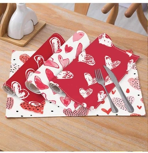 Detail of red heart pattern linen placemats showing stitching on a wooden dining table