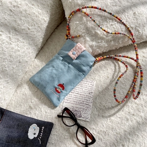 Detail of a cute denim crossbody bag with apple embroidery and colorful strap.