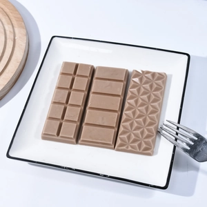 Tres tabletas de chocolate con patrones cuadrados y geométricos en un plato