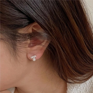 Detailed view of sterling silver pearl stud earrings with cubic zirconia on a female model