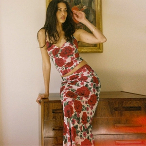 Artistic close-up of pink V-neck camisole and maxi skirt set with red floral rose print