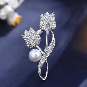 Macro shot of silver tulip brooch with clear rhinestones and a large white faux pearl