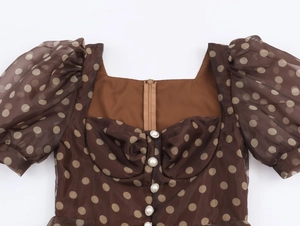 Detail of square neck brown polka dot organza midi dress with white pearl buttons
