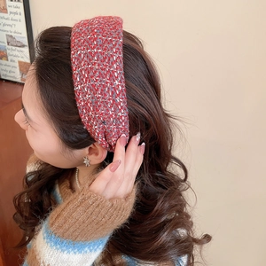Close-up of model wearing a red tweed wide headband with a woven textured pattern