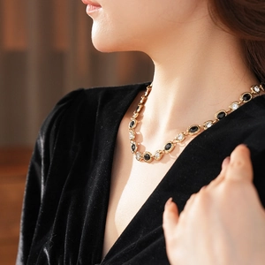 Gros plan d'un collier vintage doré avec des gemmes ovales noires et blanches