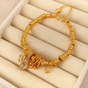 Close-up of 24k gold plated beaded bracelet with oval zircon flower pendant in jewelry box