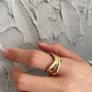 Detailed view of irregular multi-layer wavy gold ring on finger with polished finish