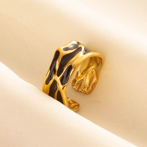 Anello aperto dorato irregolare con motivi in smalto nero su tessuto beige