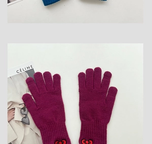Detail of pink knitted gloves with embroidered red bow decoration and soft texture