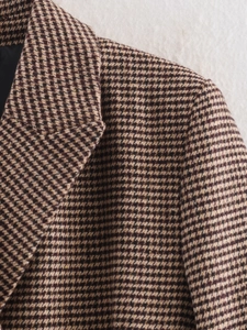 Detail of houndstooth wool blazer showing lapel structure and brown tweed texture