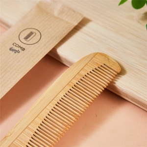 Close-up of bamboo hotel comb with eco-friendly kraft paper packaging and natural wood texture