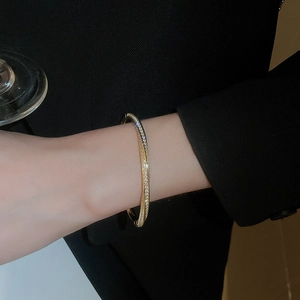 Detailed view of a layered gold-plated bracelet with pavé-set zircons on a model