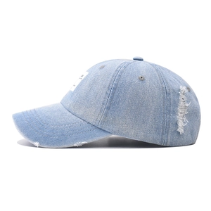 Detailed side view of washed denim baseball cap featuring distressed holes and frayed edges