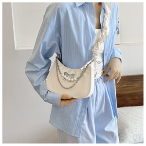 Close-up of cloud-shaped shoulder bag with silver chain and pearl bow detail