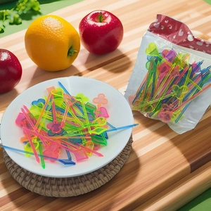 Colorful plastic mini fruit forks in heart and spade shapes on a wooden board