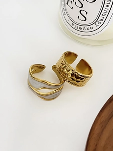 Detailed shot of gold hammered ring and wavy enamel adjustable ring on a minimalist base