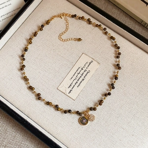 Tiger eye bead necklace with vintage gold pendants on a minimalist jewelry tray