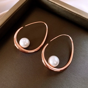 Macro detail of rose gold geometric earring with white pearl inlay on luxury display