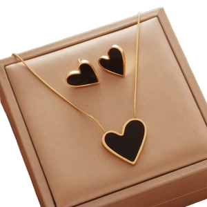 Elegant 18K gold necklace and earrings set featuring black asymmetrical heart pendants