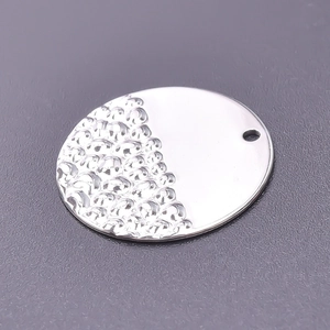 Close-up of a silver round stainless steel pendant with half-hammered texture detail