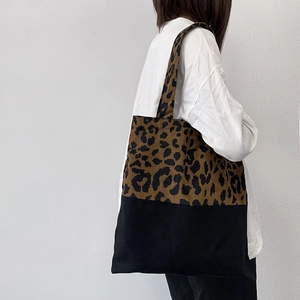 Large leopard print canvas tote bag with black stitching shown on a female model shoulder