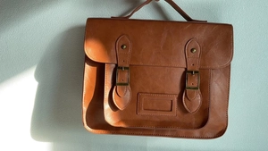 Détail de sac cartable vintage marron, sac bandoulière rétro à doubles boucles métal.