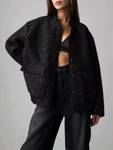 Detailed view of black sequined tweed jacket showing fabric texture and side pocket