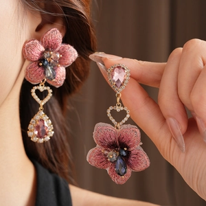 Détail de boucles d'oreilles vintage fleurs en tissu rose avec perles et pierres