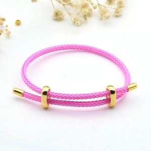 Detailed view of a pink braided rope bracelet featuring a golden adjustable buckle