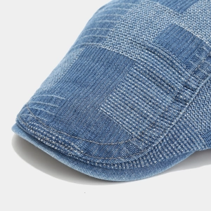Detailed macro view of denim blue newsboy cap featuring white cross-stitch woven texture