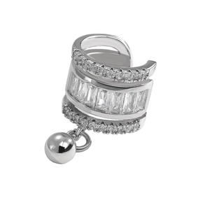 Macro detail of silver ear cuff with baguette-cut zircons and a small metal bead drop