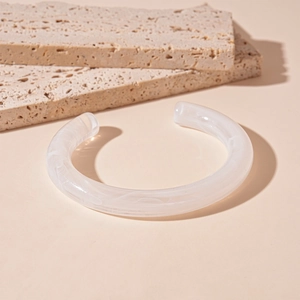 Macro detail of white marble resin cuff bracelet on minimalist stone display