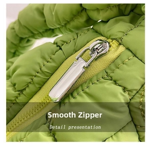 Detailed close-up of smooth silver metal zipper on green quilted puffer bag fabric