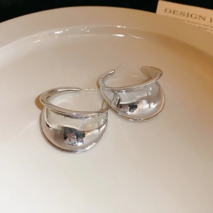 Macro detail of silver C-shape earrings with a liquid metal finish in a ceramic bowl
